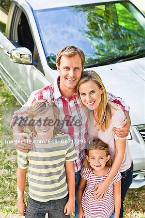 Family smiling together by car