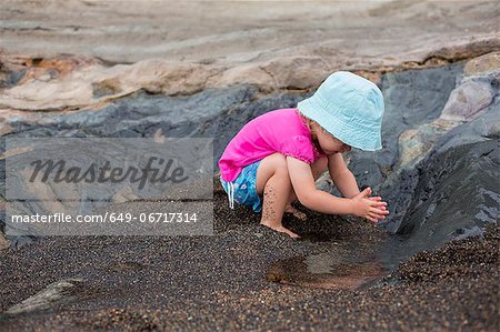 Toddler girl playing in sand on beach