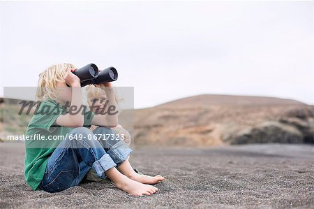Boy using binoculars on beach