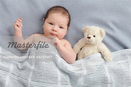 Baby boy and teddy bear laying in bed