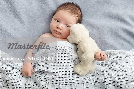 Baby boy and teddy bear laying in bed