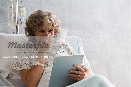 Female hospital patient with digital tablet, laughing