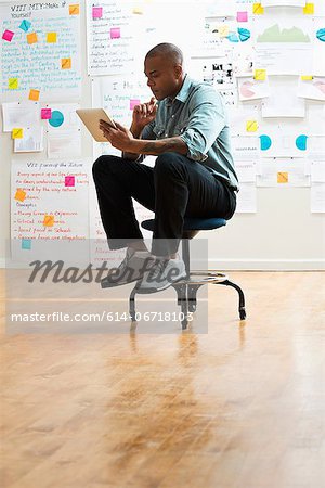 Man sitting on stool with digital tablet