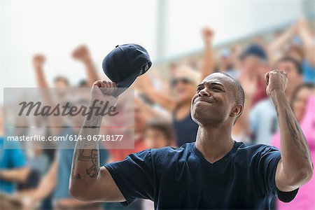 Man sports game, holding baseball cap and looking frustrated