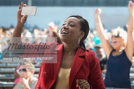 Woman in stadium, recording event with her phone