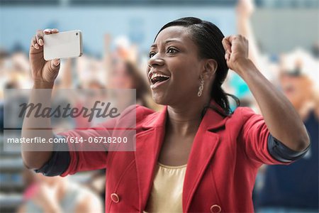 Woman in stadium, recording event with her phone