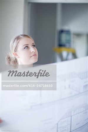 Woman holding blueprints in home