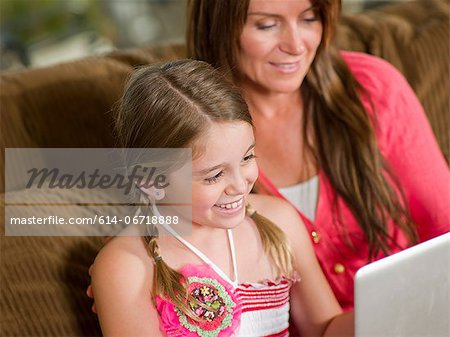 Mother and daughter using laptop on sofa Mother and daughter using laptop on sofa