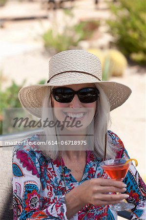 Older woman having cocktail outdoors