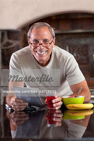 Older man reading newspaper at breakfast
