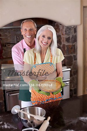 Older couple holding pie in kitchen