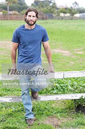 Man leaning on wooden fence