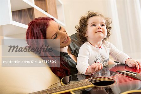 Mother and daughter with guitar on sofa