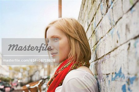 Woman leaning on brick wall