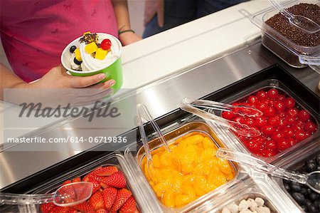 Girl putting toppings on frozen yogurt Girl putting toppings on frozen yogurt