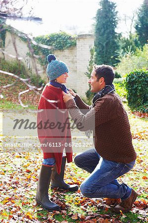 Father tying son's scarf outdoors