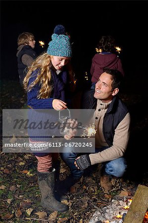 Father and daughter playing with sparkler