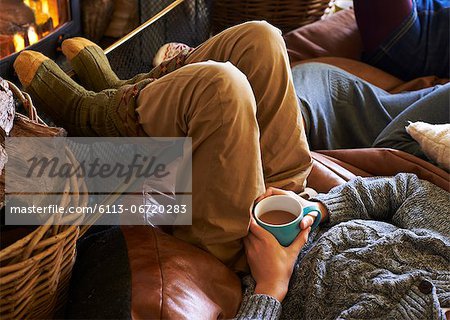 Boy drinking cup of coffee by fire