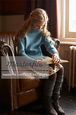 Girl reading book in armchair