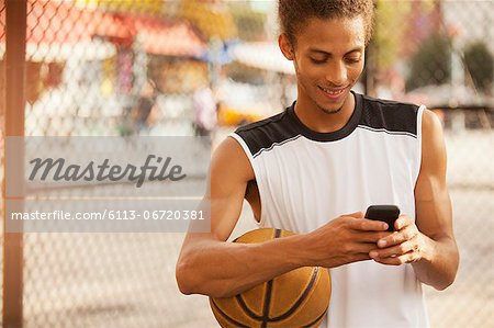 Man using cell phone on basketball court