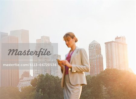 Businesswoman using cell phone in urban park