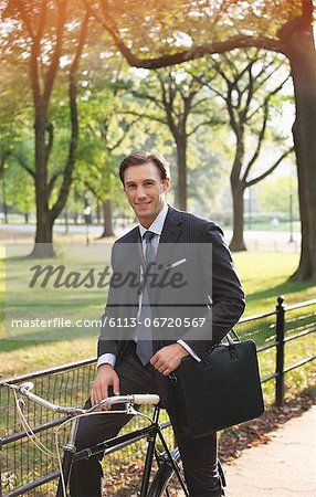 Businessman sitting on bicycle in urban park