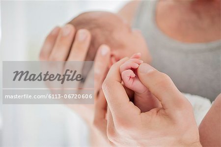 Mother cradling newborn baby's hand