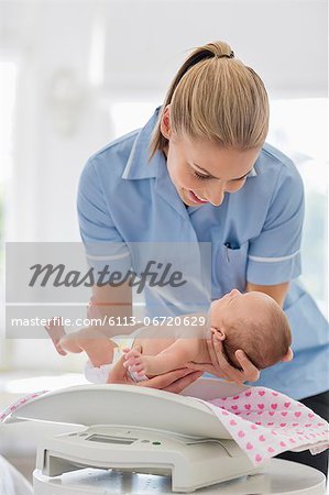 Nurse weighing newborn baby
