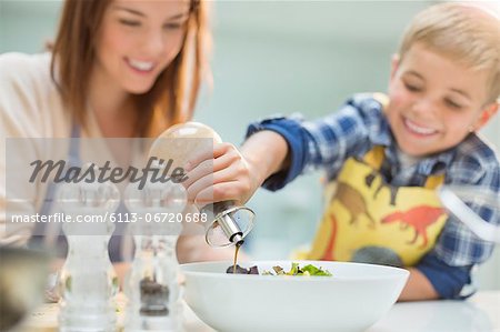 Mother and son making salad in kitchen