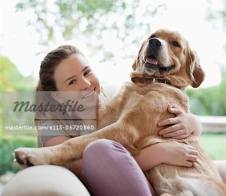 Smiling girl hugging dog on sofa