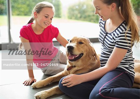 Girls relaxing with dog in living room