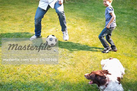 Boy playing soccer with dog outdoors