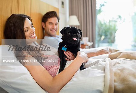 Couple relaxing with dog in bed