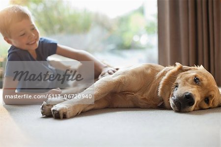 Smiling boy petting dog in living room