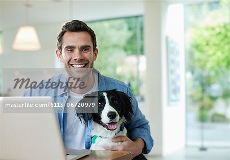 Man with dog using laptop in kitchen