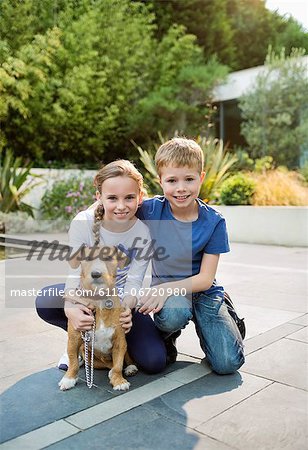 Smiling children petting dog outdoors