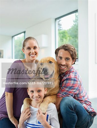 Family smiling with dog indoors