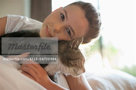 Girl petting cat on bed
