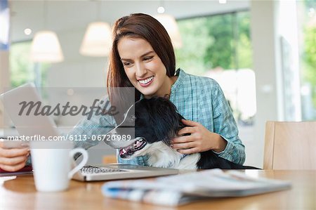 Woman with dog on lap using laptop