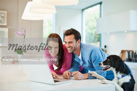 Couple using laptop with dog at table