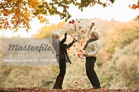 Older couple playing in autumn leaves