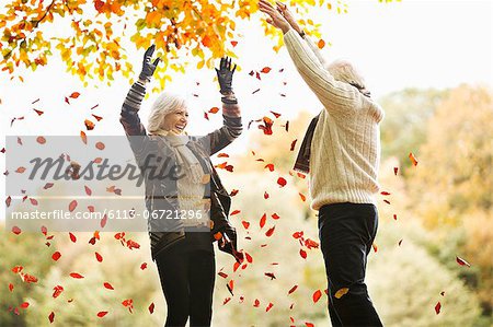 Older couple playing in autumn leaves