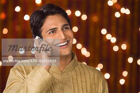 Man talking on a mobile phone in front of Diwali decoration