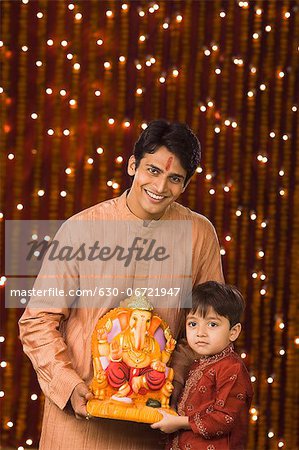 Father and son holding an idol of lord Ganesha
