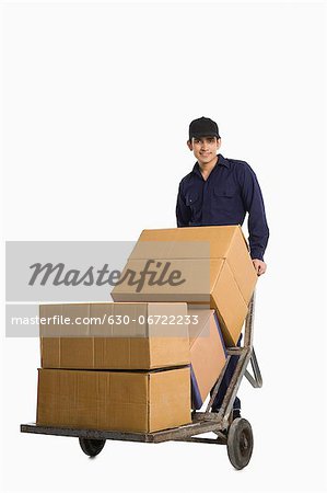 Delivery man pushing cardboard boxes on a hand truck