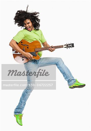 Man jumping in the air while playing a guitar
