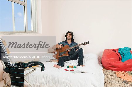 Man playing a guitar in the bedroom