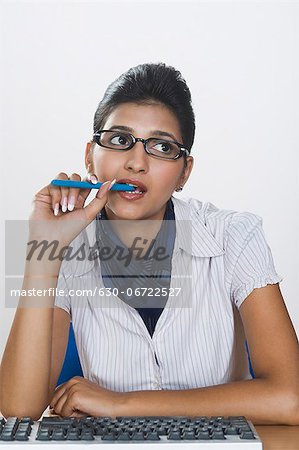 Businesswoman biting a pen and thinking