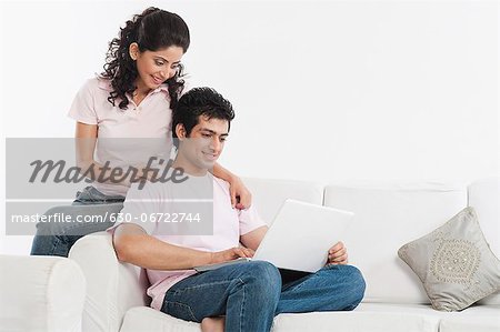 Couple sitting in a couch and using a laptop