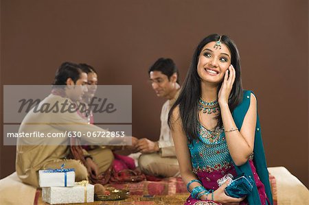 Woman talking on a mobile phone with her family in the background